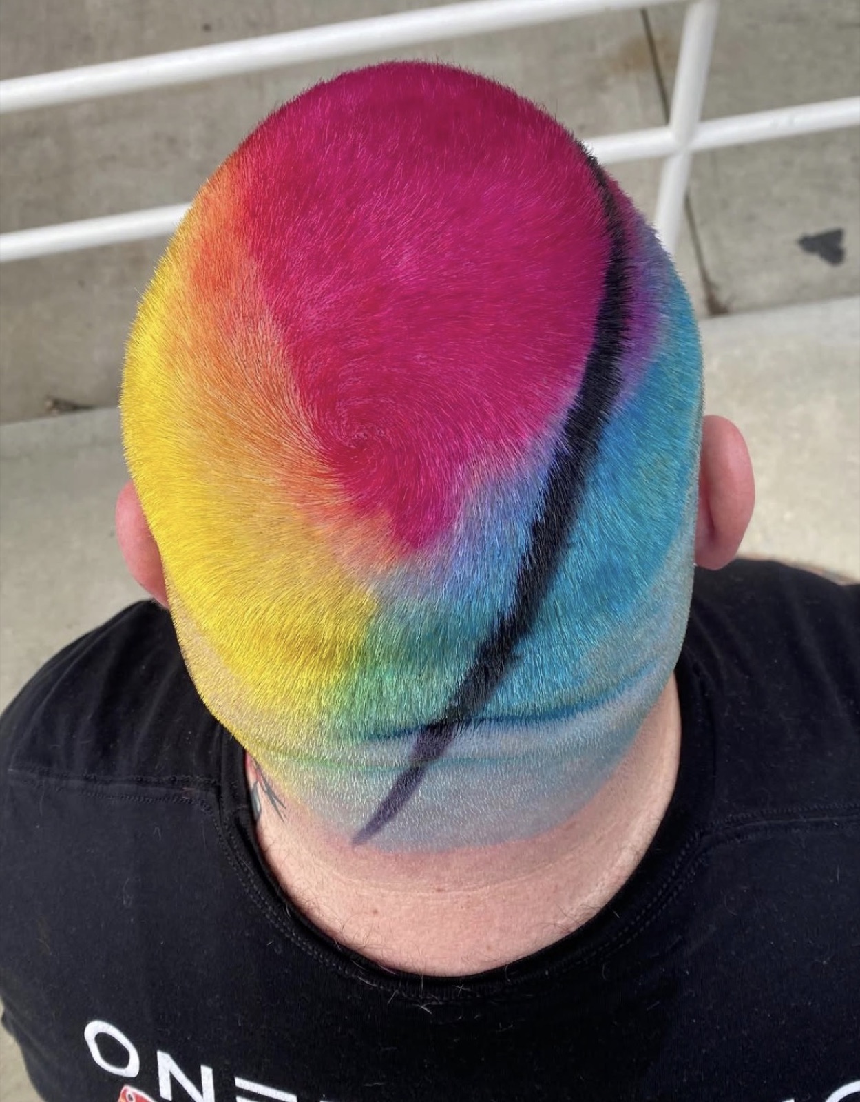Rainbow scalp art on shaved head, top-down view